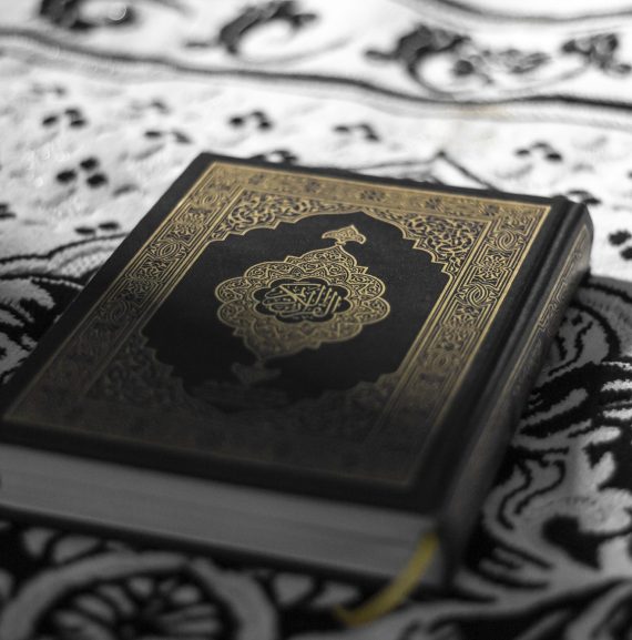 Closeup of a Quran with intricate book cover design, on a rug