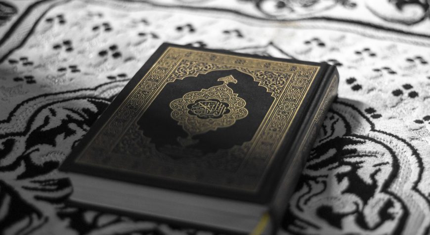 Closeup of a Quran with intricate book cover design, on a rug