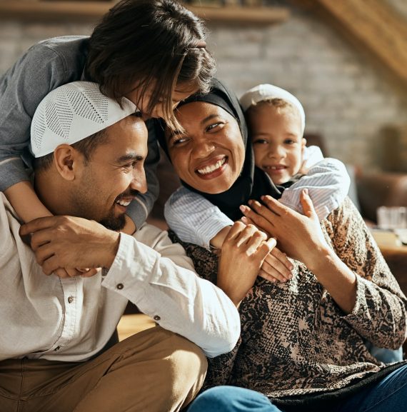 Happy Muslim kids embracing their parents and having fun at home.