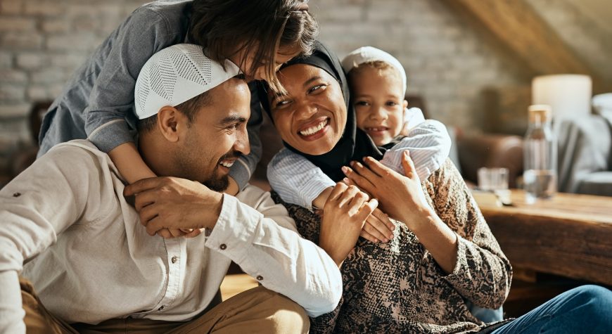 Happy Muslim kids embracing their parents and having fun at home.